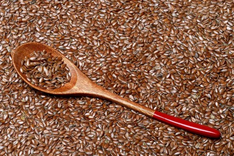 Linseed with wooden spoon, seeds of the common flax (Linum usitatissimum)