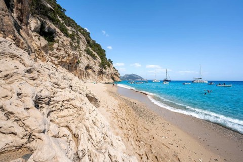 Sandy beach beach and steep cliffs at Cala Luna, Golfo di Orosei, Baunei, Sardinia, Italy