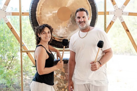 A man and woman, both sound therapists, standing looking at camera while engaged in a therapeutic