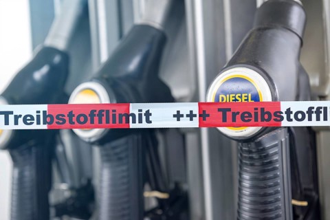 (photo montage) Barrier tape with the inscription FUEL LIMIT in front of the gas pumps of a gas