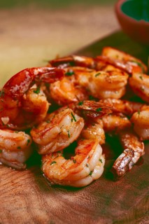 Fried tiger prawns, jumbo, in garlic sauce, in butter, with herbs, on a wooden board, homemade, no