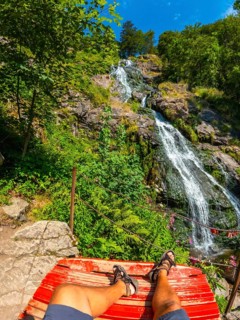 Man sitting in summer under the Todtnau waterfall in the Black Forest in Germany