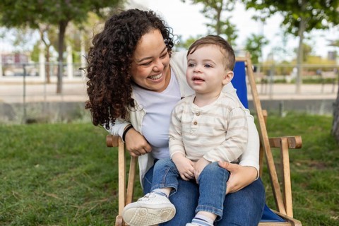 A joyful mother and her baby enjoy a sunny day in the park, sharing laughter and creating cherished