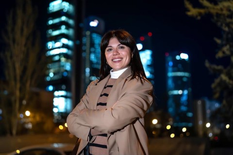 Young professional woman smiling at camera, crossing arms, standing confidently in an urban