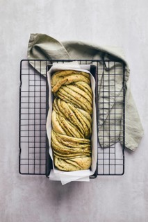 Baked homemade savoury babka plaited bread loaf flavoured with cheese and pesto, in the making tin