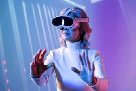 An elderly Asian woman wearing a virtual reality headset, interacting with a digital environment.