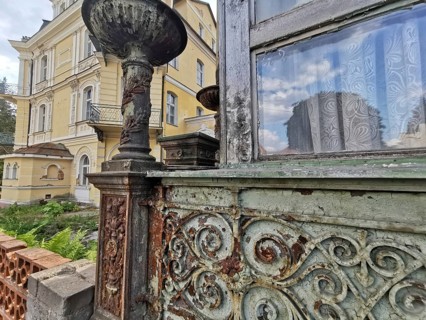 An old, dilapidated building with rusted decorations and windows with nostalgic curtains, villa in