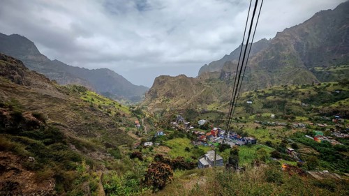 View of a green valley and a small village in a mountainous landscape, hiking from Cova Crater