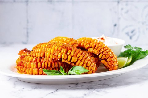 Corn ribs, with cream sauce, spices and lime, appetizer, on a white plate, homemade, no people