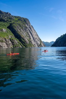 Two kayakers with red kayaks in the fjord Trollfjord, mountains reflected in the water, fjord
