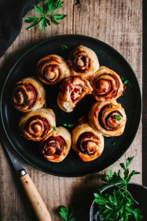 Delicious chorizo-filled bread rolls arranged on a rustic wooden table. Fresh parsley adds a pop of
