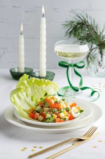 A beautifully arranged plate of salmon Olivier salad, garnished with fresh greens and egg, served
