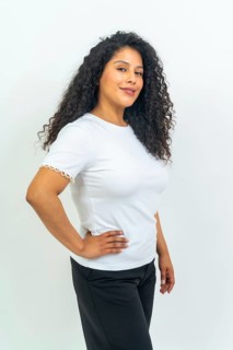 Studio portrait with white background of a latin woman with curly hair standing proud hand on hip