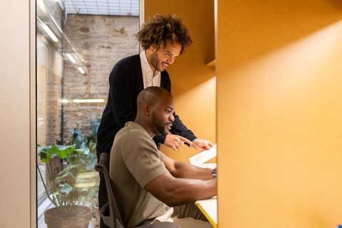 Two professionals collaborate in a vibrant coworking space in Barcelona. The open-plan office