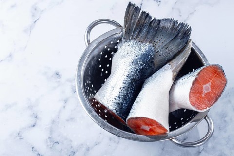 Fish tails are placed in a colander on a marble counter. The colander allows water to drain away