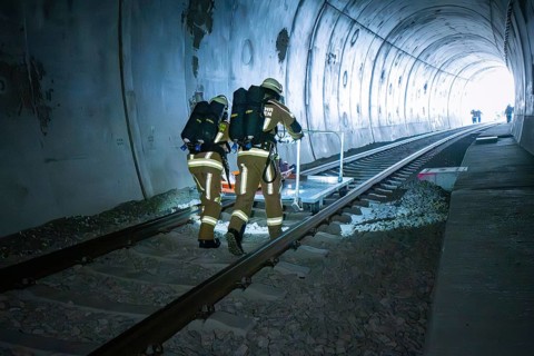 Firefighters move along the rails in the tunnel with equipment, fire brigade exercise on the