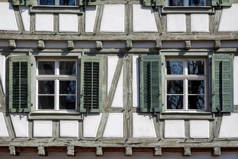 Detailed view of a classic half-timbered house with lattice windows, shutters and beam heads, Old