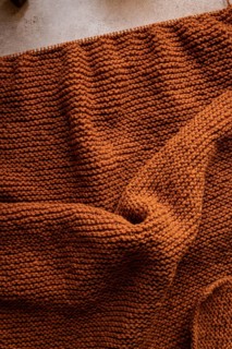 A close-up view of a cozy, brown knitted fabric, showcasing its intricate texture. Perfect for