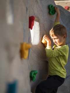 Seven year old boy climbing at artificial wall