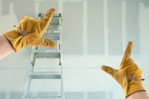 Contractor Hands In Leather Gloves Framing New Blank Drywall