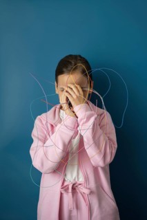 A child in a pink outfit stands against a blue background, tangled in colorful wires, symbolizing