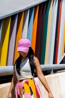 A woman in a colorful outfit stands against a backdrop of modern architecture. Her vibrant attire