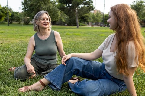 A joyful moment between mother and daughter as they relax on a sunny day in the park. Both are