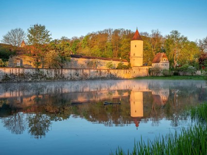 Digestive tower with park guard house on the city wall in morning light, reflection in the