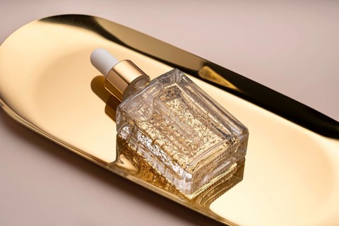 Luxurious anti aging face serum packaged in a clear glass bottle with shimmering gold flakes,
