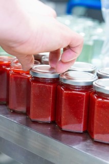 Person closing jars of red jam on a table, jam production, Haselstaller Hof, Wildberg Gültlingen,