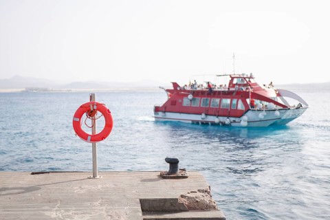 The image captures a vivid port scene with a bright red ferry approaching In the foreground, a