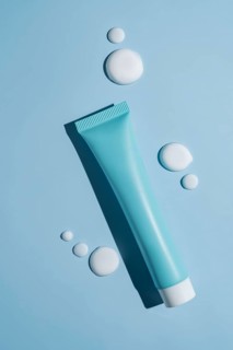 A sleek cosmetics package sits elegantly on a blue background, accented by smooth, artistic smears