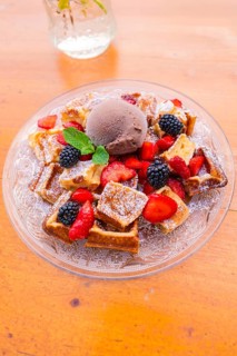 Top view of waffles with berries and a scoop of chocolate ice cream on a glass plate, Cafehäusle