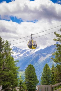 Cable car over the Alps, with snow-covered mountains and forest in the background, Penken,