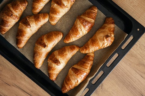 Delicious homemade croissants freshly baked to golden perfection, cooling on a parchment lined