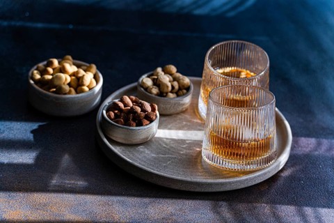 Spiced cognac cocktail featuring cinnamon and star anise, accompanied by almonds, peanuts, and
