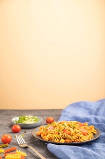 Tortiglioni semolina pasta with tomato and microgreen sprouts on a black and orange background and