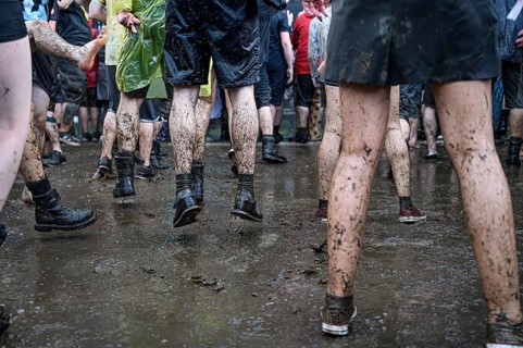 Dirty legs of people dancing in the mud during concert