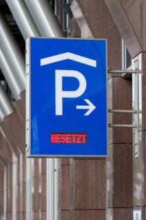 Blue car park sign with white P symbol and red display with the words 'Occupied' in front of modern