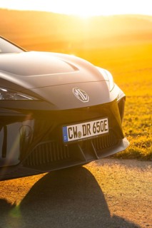 Black car from the front with sunset in the background in a rural setting, e-car sharing vehicle