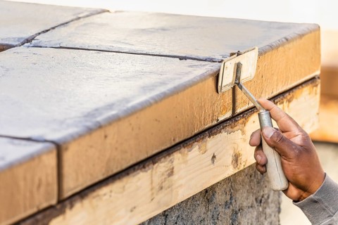 Construction Worker Using Hand Groover On Wet Cement Forming Coping Around New Pool