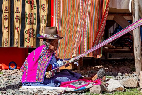 Side view of a person weaving colorful fabrics in traditional clothing, Elderly traditionally
