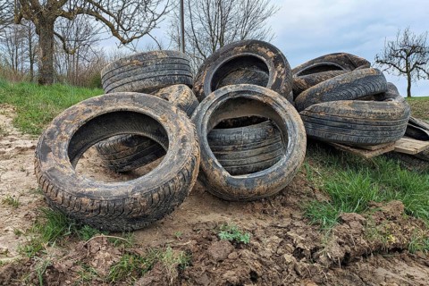 Pile of old tires dumped in nature. Illegal waste disposal and environmental pollution