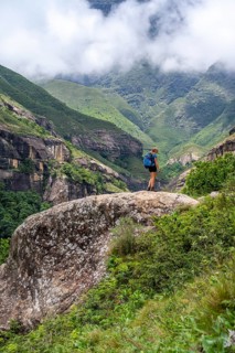 Female hiker standing in front of landscape with mountains and fog, Drakensberg National Park,