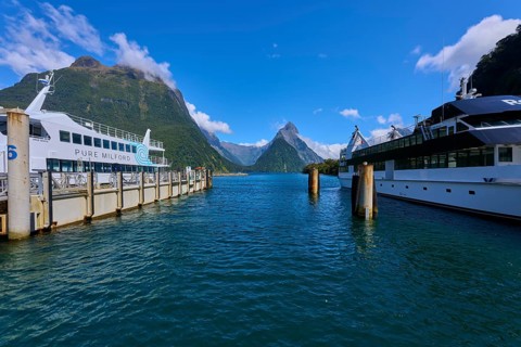 Harbour with large ships in the foreground, framed by majestic mountains and clear sky, summer,