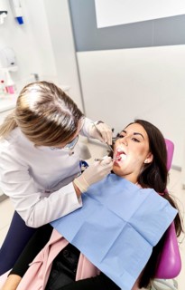 A dentist performs an oral examination on a patient in a bright, modern dental clinic. The patient