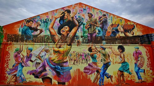 Dynamic mural, mural, graffiti showing people dancing and playing music in vibrant colors, hangar,