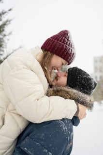 A loving couple shares a joyful embrace in a snowy outdoor setting Their warm winter clothing,