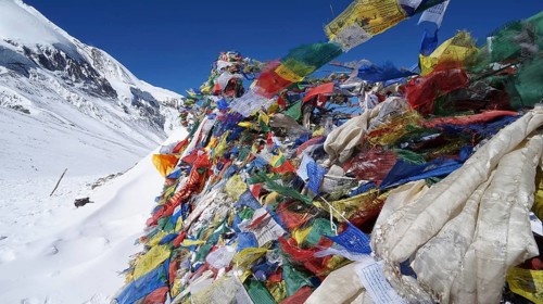 Colourful prayer flags fly near snow and mountain scenery in the Himalayas, Thorong La, Manang,