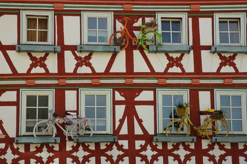 Brown-red house wall of half-timbered house with flower decoration and three bicycles as